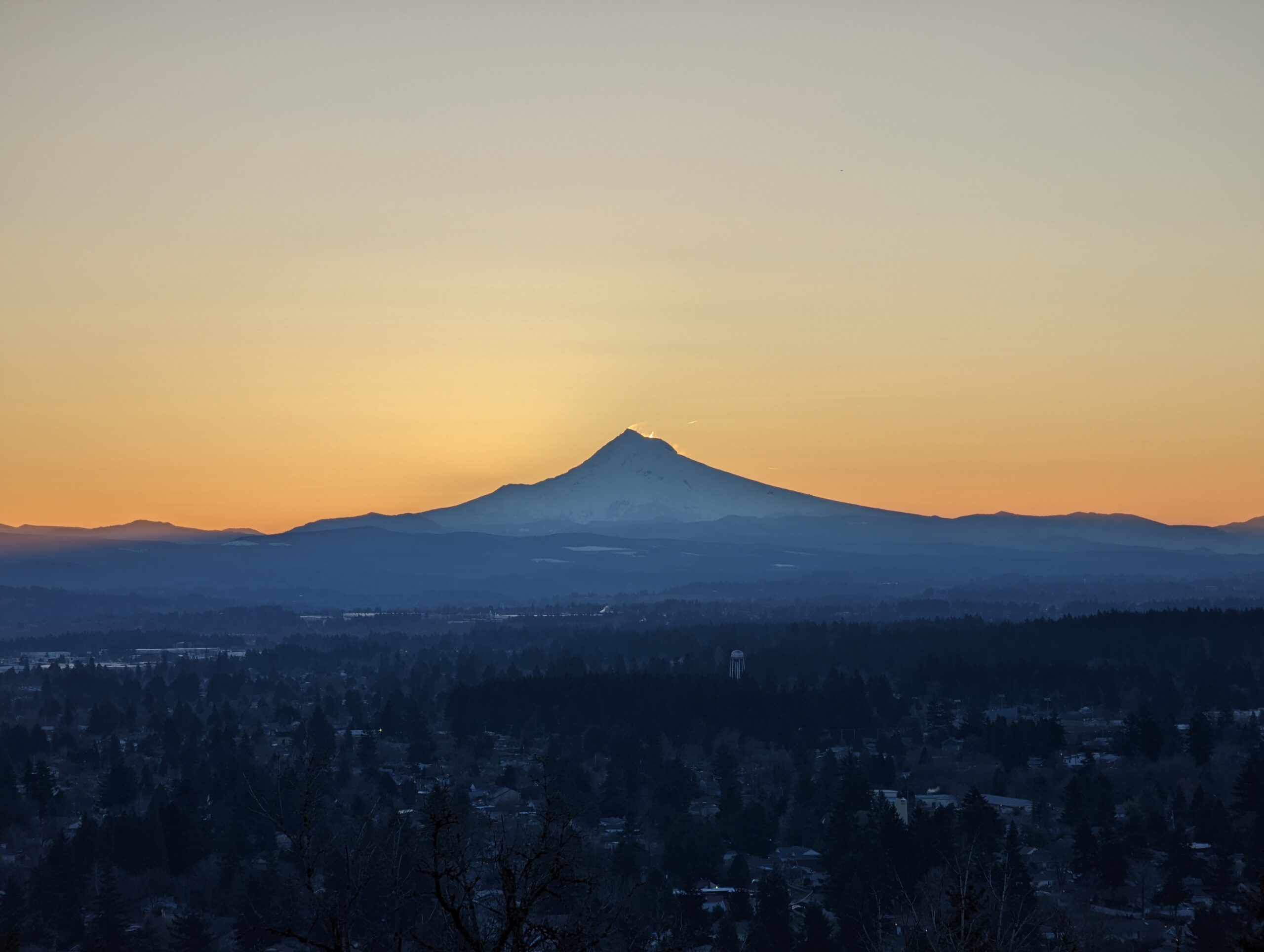 Mount Hood as seen from Rocky Butte before sunrise. The sun is starting to appear in the wind-blown snow from the summit.