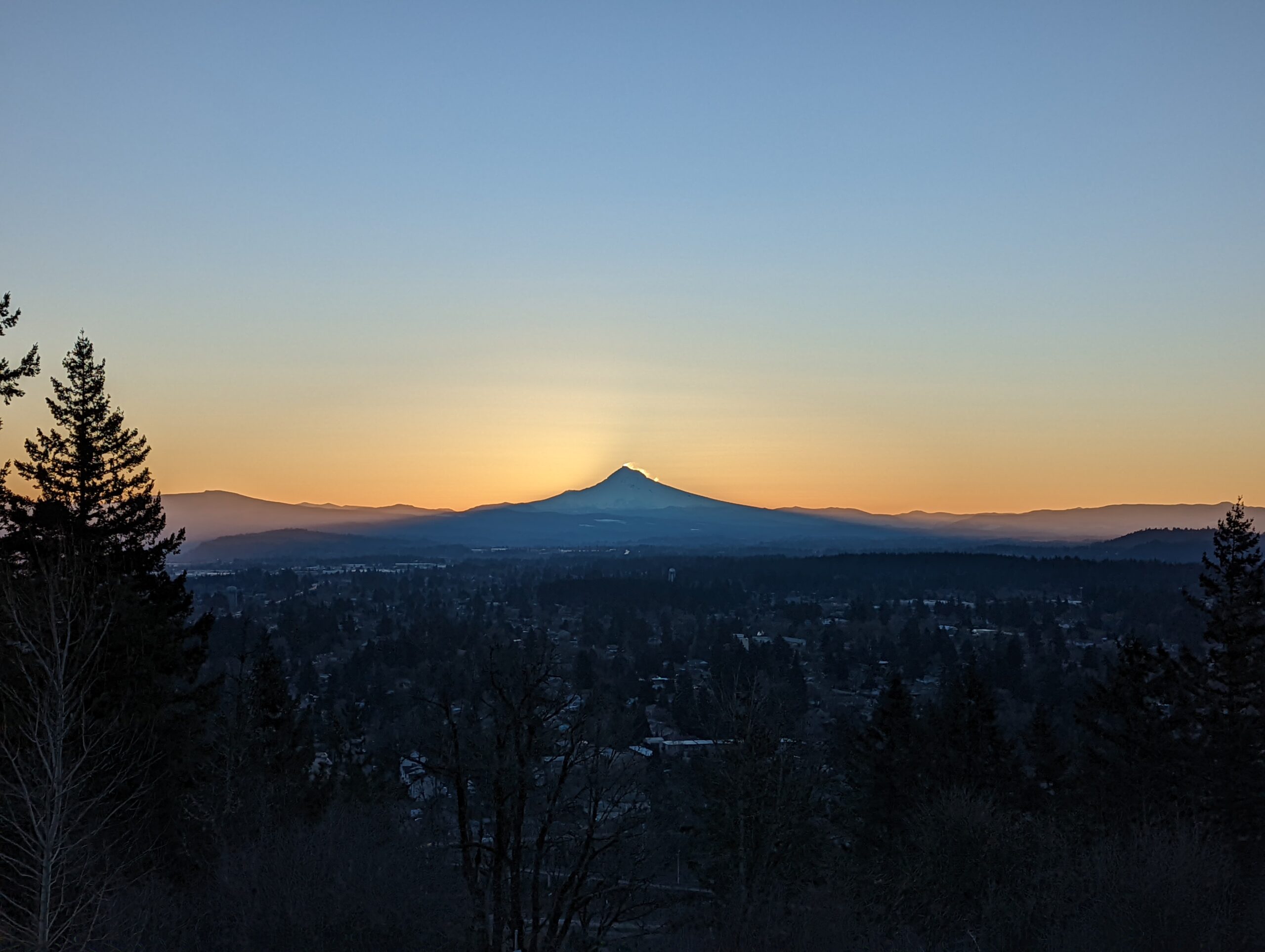 Mount Hood as seen from Rocky Butte before sunrise. The sun is starting to appear in the wind-blown snow from the summit.