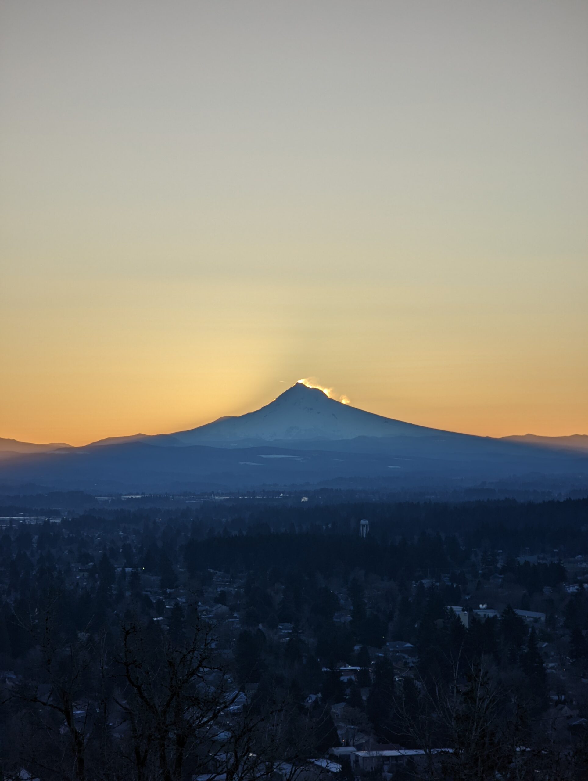 Mount Hood as seen from Rocky Butte before sunrise. The sun is starting to appear in the wind-blown snow from the summit.