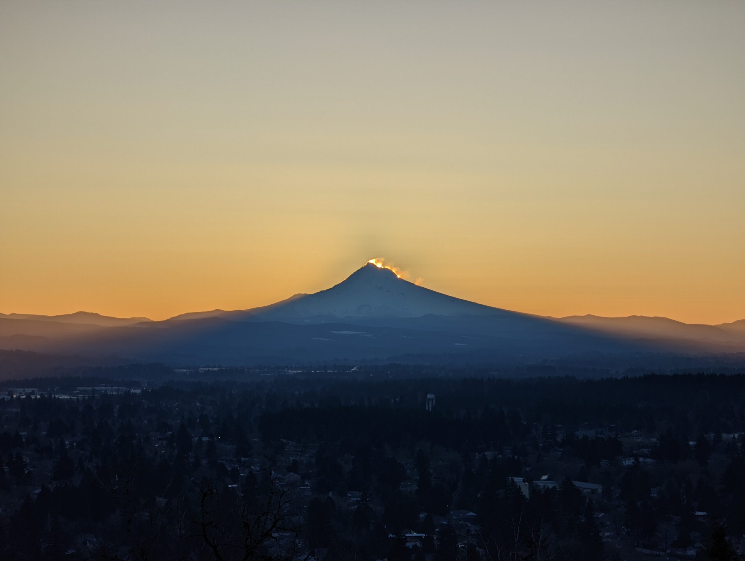 Mount Hood as seen from Rocky Butte before sunrise. The sun is starting to appear in the wind-blown snow from the summit.