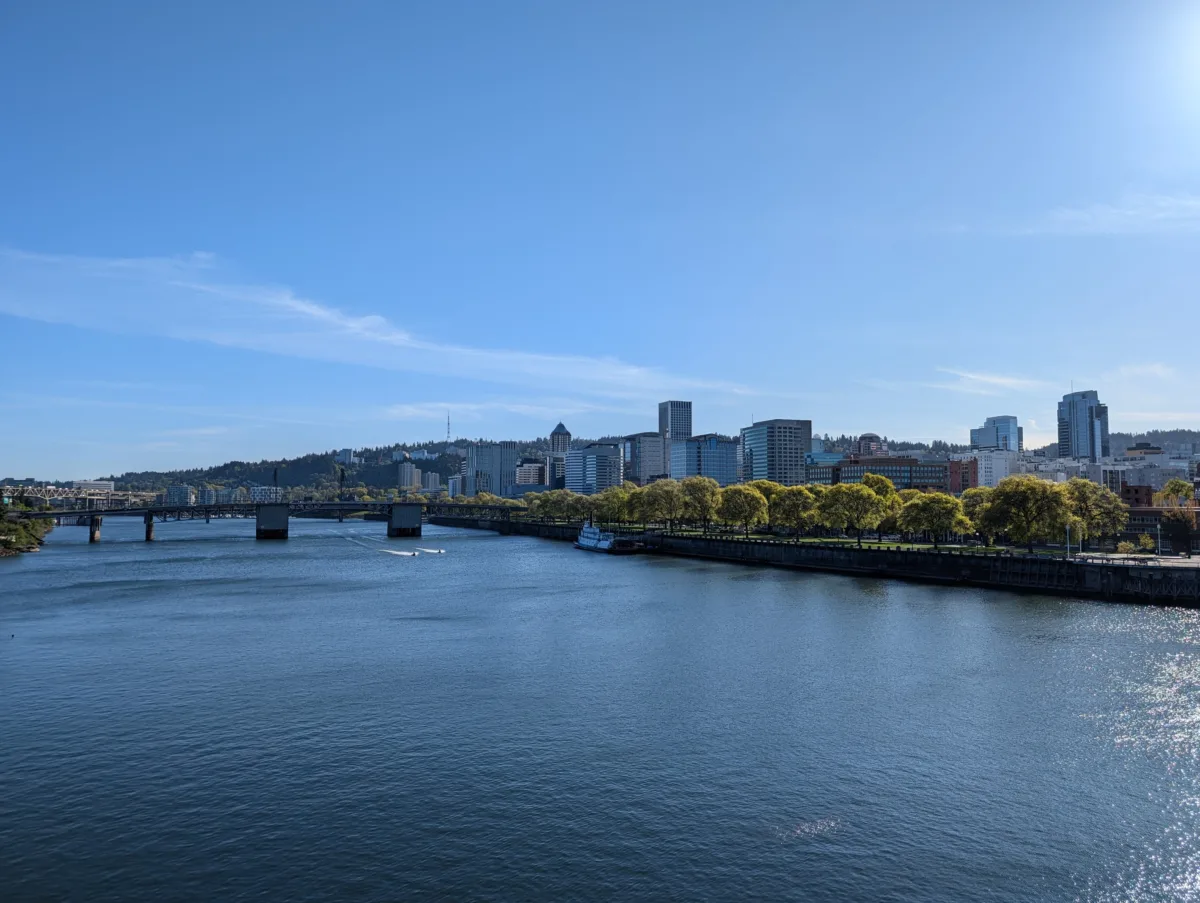 Portland, Oregon as seen from the Burnside Bridge in the late afternoon with a beautiful blue sky and the Willamette River in the foreground.